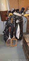 Photo showing two golf bags filled with right-handed golf clubs plus a pair of white men's golf shoes size 12 on top of clubs.