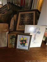 General view of all artworks including paintings and print leaning against a mirror and furniture.