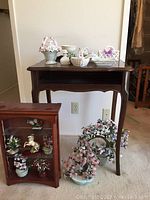 Full view of curio shelf with some flower baskets on top and multiple flower arrangements on floor beside it