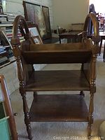 Wooden shelf unit showing three tiers and turned legs