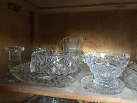Shelf display showing multiple cut glass serving pieces including platters and pitchers with intricate diamond cut patterns.