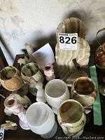 Photo showing multiple Mexican onyx cups, vases, pink onyx candle holders, various figurines, and a carved white onyx bookend.