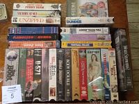 Stack of 20 VHS movies showing titles including Funny Farm, Victory at Sea, Unzipped, Caddyshack II, Don Juan DeMarco, Dundee, Full Metal Jacket.