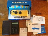 Overview of Minolta Weathermatic-A camera in original box, alongside HP 10B calculator, manuals, and accessories on wooden table.