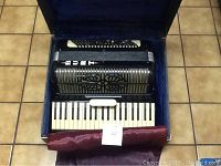 Accordion in open case showing keyboard and decorative grille.