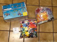 Photo showing K'Nex building set in original box along with two bags of assorted toy building bricks.
