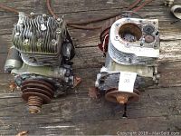 Two large Kawasaki FB460V engines side by side on wooden floor, one with visible cylinder head and cooling fins, the other missing the cylinder head showing internal piston chamber.