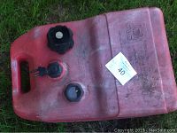 Red plastic boat engine fuel tank with caps visible on top, showing handle and surface wear.