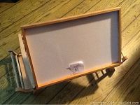 Top view of the lap table showing lifted top surface with wooden frame and paper or board mounted on top.