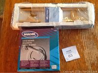 Overview photo showing Invacare hand shower box and Glacier Bay oak towel bar in packaging.