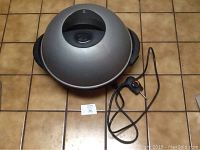 Top view of dome-shaped silver lid with black handle and attached temperature control with power cord