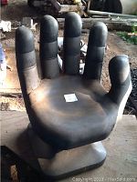 Black plastic hand-shaped chair viewed from the front showing overall shape and design.