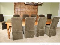 Front view of long pine dining table with eight upholstered chairs around it, highlighting size and style.