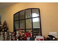 Full view of large window-shaped mirror with cast iron trim, showing grid panes and arched top.