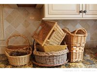 Group photo of six woven baskets in various shapes, sizes, and natural colors placed on a kitchen countertop