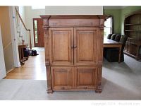 Front view of Lloyds solid wood entertainment cabinet showing closed paneled doors and decorative molding.