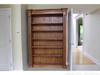 Front view of large solid wood bookcase showing five shelves and decorative molding