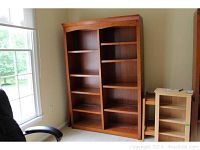 Full view of the large double-sided wooden bookcase near window and in room with carpet