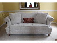 Front view of beige corduroy camelback sofa with three throw pillows