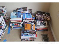 Full view of stacked baseball and literature books on carpet in a corner of a room.