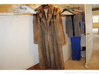Full front view of the raccoon fur coat hanging in closet, showing length and fur texture.