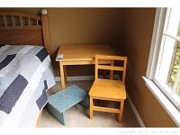 Small wooden child's table, chair, and blue-green painted step stool positioned near a bed and a window in a carpeted room.