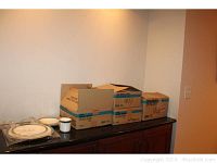 Photo of cardboard boxes containing the boxed dinnerware sets and some plates with cups on top.