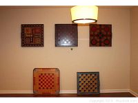 Five pieces of game board wall art and trays shown on a beige wall and floor to illustrate size and appearance.