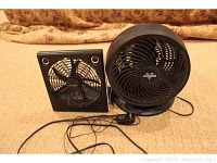 View of both fans showing the O2 Cool speaker fan on the left and the larger round Vornado fan on the right, cords visible.