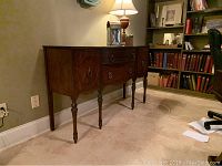 Full view of the Duncan Fife wooden sideboard against a wall, showcasing its shape, legs, and finish.
