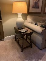 Full view of vintage wooden drop leaf end table beside sofa with lamp on top illustrating size and condition