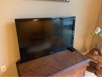 Samsung 44-inch television sitting on a wooden cabinet, screen off.