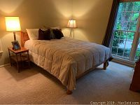 Queen bed frame in a bedroom with a comforter and pillows showing the overall condition and design.