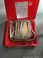 Aluminum fire escape ladder folded inside a red hard plastic carrying case with safety chain attachments visible