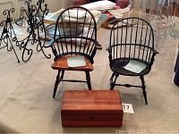 Front view of two wooden doll chairs and wooden box arranged on table, showing chair design and box finish.