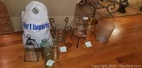 Full lot overview showing vases, glass bottles, candle holder, faux decorative fruit, and trash cans
