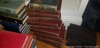 Stack of various vintage and modern books including some with red, blue, and maroon covers