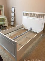 Full view of assembled white IKEA Hemnes bed frame showing headboard with slats and solid footboard on carpeted floor