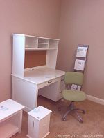 Desk with attached hutch shelves and drawers, green chair beside it, items arranged in corner of room with carpeted floor