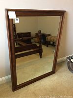 Full view of the rectangular mirror showing the wooden frame and reflective surface.