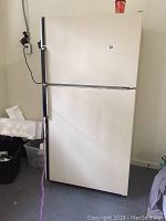 Front view of white Kenmore top-freezer refrigerator showing exterior and handle.