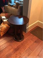 Full side view of the round walnut side table showing the vertical slats base and circular top.