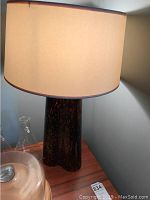 Table lamp on wooden surface with curved dark base and beige shade