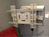 Front view of the silver metal TV wall mount bracket with adjustable vertical arms and central mounting plate attached to the wall.