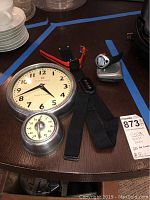 Overview of all items on table including wall clock with timer, heart rate sensor band, wrist GPS tracker, and TIMEX Speed and Distance trackers