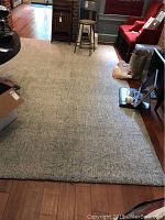Full view of large area rug on hardwood floor in room with furniture around edges