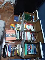 Long view of multiple stacks and boxes of books on floor including cookbooks and reference books, visible titles include 'The New American Cuisine', 'Book of Soups', 'Czech Slovak Dictionary' and others