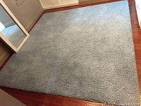Full view of the light blue 8ft x 8ft area rug on hardwood flooring