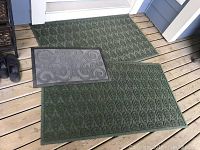 Photo of three outdoor mats arranged on wooden deck, showing the size difference and patterns on each mat.