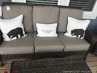 Front view of three-seat wicker patio sofa with cushions and decorative pillows